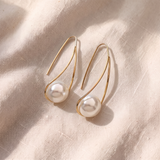 Brincos dourados pendentes elegantes com pérolas