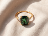 Anel elegante de dourado adornado com zircões verdes brilhantes