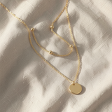 Colar dourado elegante de duas camadas com satélites e pendente em forma de moeda