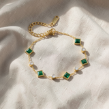 Elegante pulseira dourada com esmeralda quadrada e detalhes de cristais brilhantes